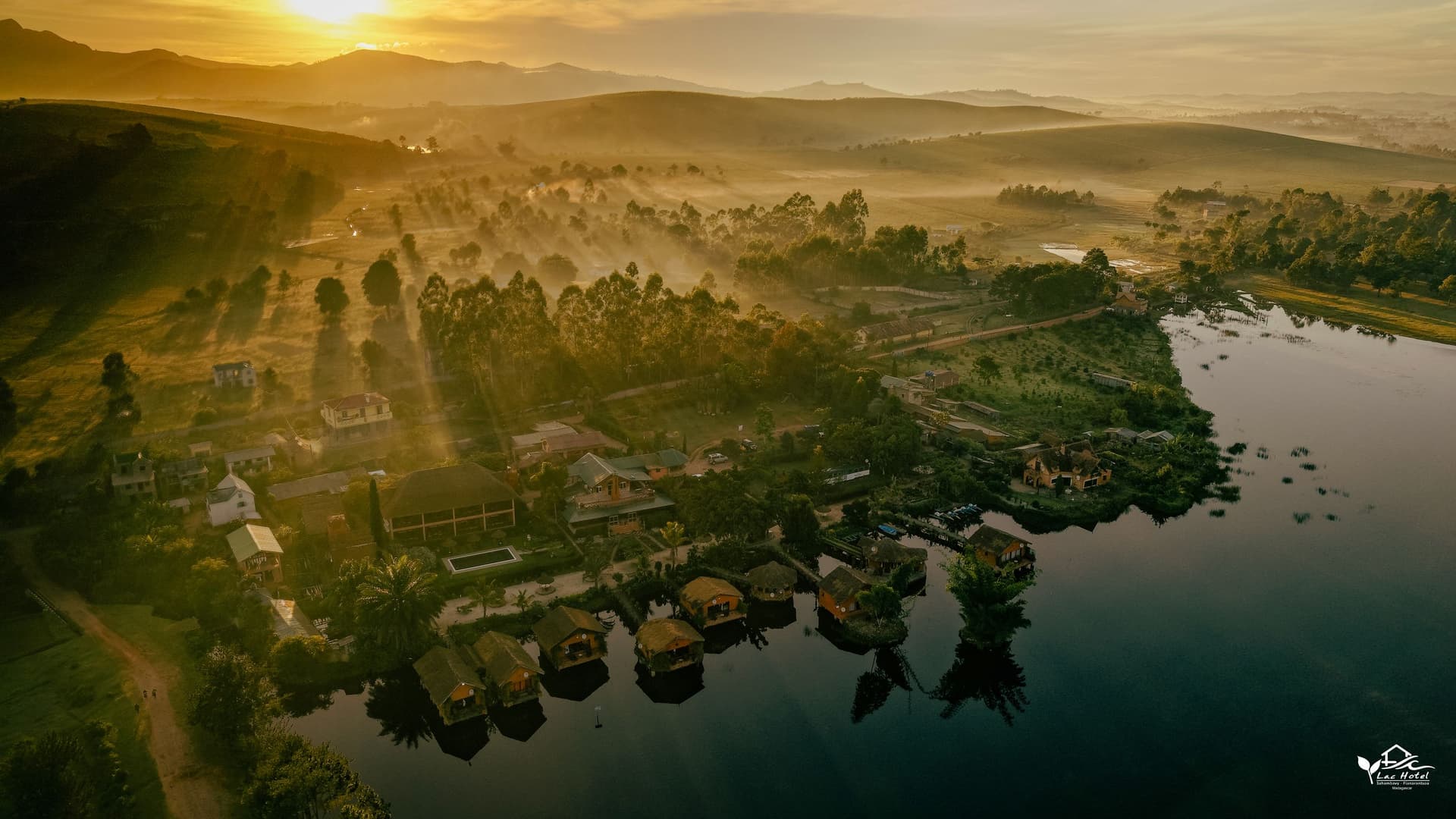 Lever de soleil sur le Lac Hôtel Sahambavy, les bungalows sur pilotis et les collines, vus au drone