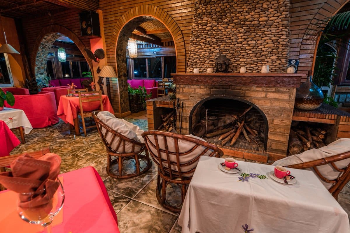 Stone fireplace and set tables in the restaurant at dusk