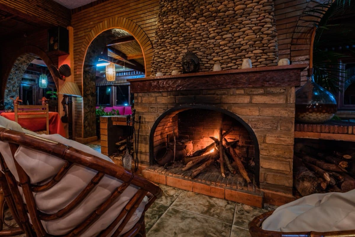 A lit fire and the bar's rattan armchairs at dusk