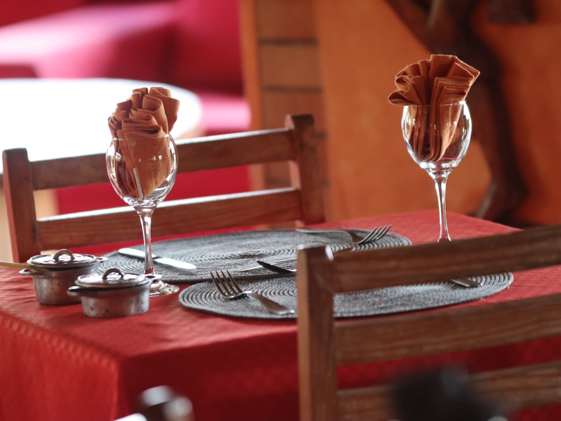 Table dressée à la nappe rouge, serviettes pliées dans les verres à vin